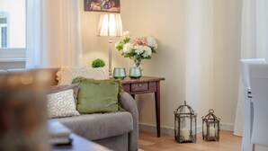 A cozy living room with a sofa, a small table with decorative items, and a painting on the wall. - Casa Ugolino in Lucca (Lucca)