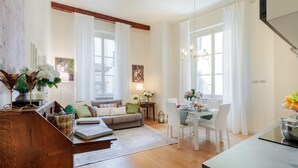 A modern living room with a sofa, dining table, and chairs. There is a staircase leading to another level. - Casa Ugolino in Lucca (Lucca)