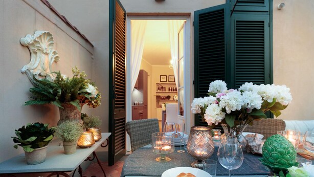 A dining table set with candles, flowers, and a bread basket in a cozy outdoor setting. - Casa Brumar in Lucca (Lucca)