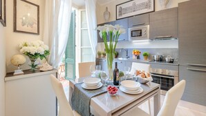 A modern kitchen with stainless steel appliances, a dining table set for four, and decorative elements like flowers and a globe. - Casa Brumar in Lucca (Lucca)
