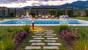 A pool area with a pergola, lounge chairs, and a stone wall backdrop. - Villa Hugo in Lucca With 5 Bedrooms and 6 Bathrooms (Lucca)