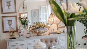 A well-lit room with a large mirror, a decorative bowl, and a vase with flowers on a dresser. - Villa Dana in Segromigno in Monte (Capannori)
