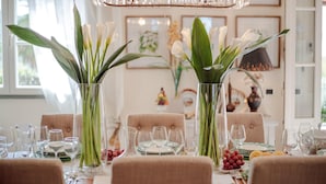 A dining table set for six with clear glassware, green asparagus, and white flowers. - Villa Dana in Segromigno in Monte (Capannori)