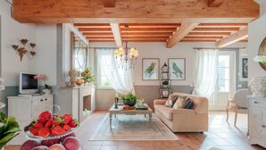 A spacious living room with a high wooden ceiling, a comfortable sofa, a coffee table, and a television on a cabinet. - Villa Regina in Lucca (Lucca)