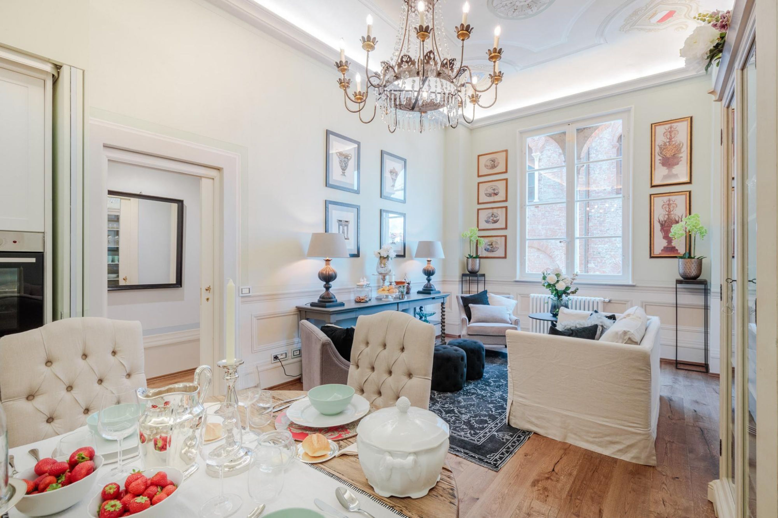 A dining area with a table set for a meal, a chandelier, and framed artwork on the walls.