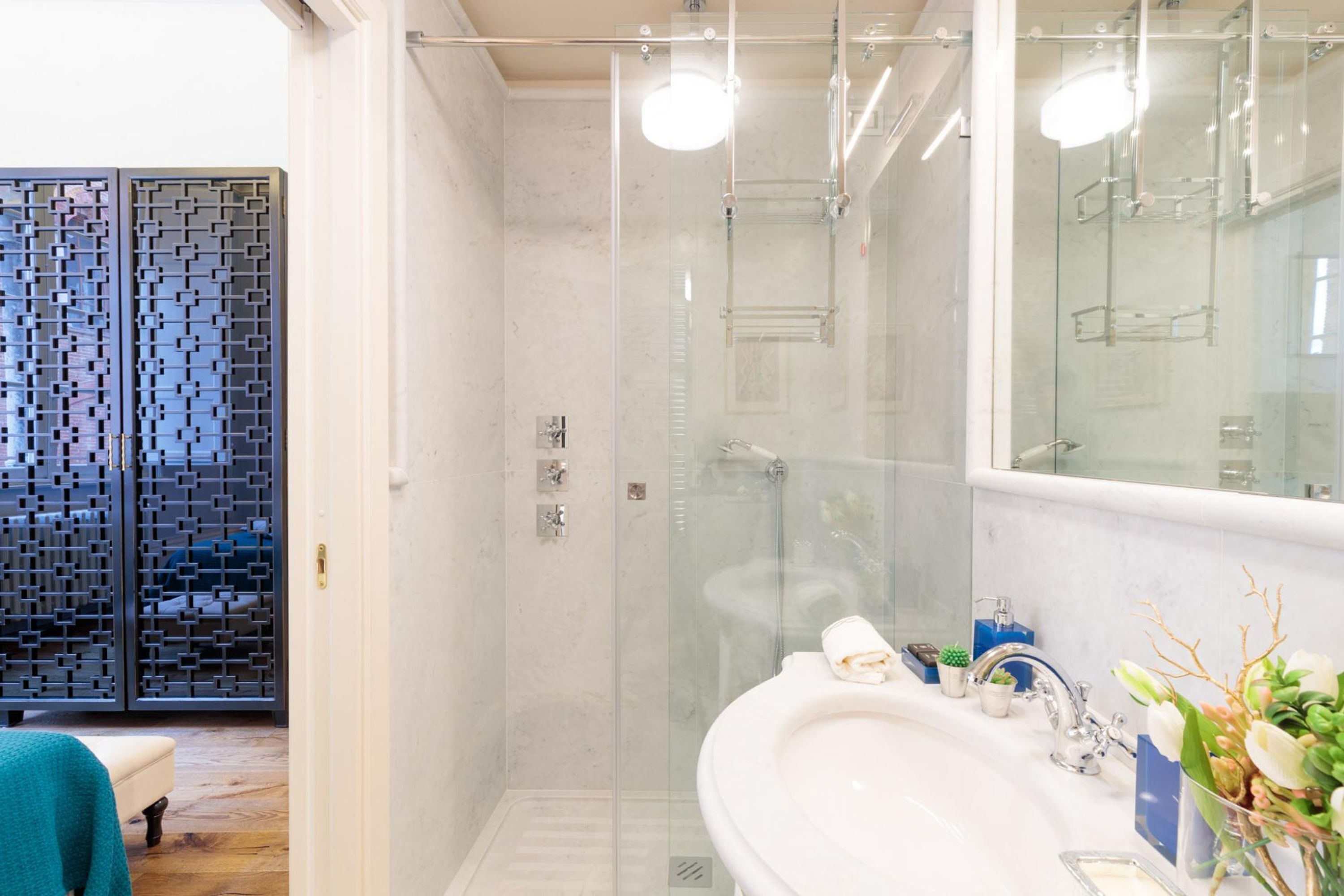 Un baño moderno con ducha acristalada, un lavabo blanco y un espejo.