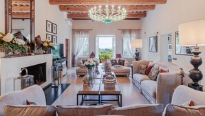 A spacious living room with a fireplace, sofas, a coffee table, and a chandelier. - Villa Duemani - Pickleball Retreat (Capannori)