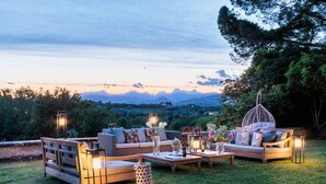 An outdoor seating area with a sofa, chairs, and a coffee table, set against a backdrop of mountains and trees. - Villa Duemani - Pickleball Retreat (Capannori)