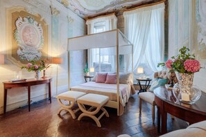 A luxurious bedroom with a four-poster bed, a sitting bench, and a vanity table with a mirror. - Casa Penelope in Lucca (Lucca)