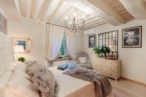 A bedroom with a large bed, a chair, a dresser, and a chandelier. - Casa Blanc in Lucca With 1 Bedrooms and 1 Bathrooms (Lucca)