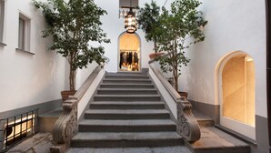 A staircase with ornate stone balustrades, flanked by potted trees, leading to a warmly lit entrance. - Appartamento Caruso in Sorrento (Sorrento)