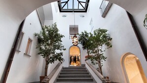 A staircase with a skylight, flanked by trees and leading to a warmly lit interior space. - Appartamento Caruso in Sorrento (Sorrento)