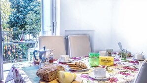 A dining table with a floral tablecloth, a loaf of bread, a cheese wheel, and a coffee pot. - Maison Palazzo Correale (Sorrento)