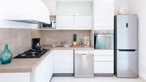A modern kitchen with white cabinets, a stainless steel refrigerator, a built-in oven, a dishwasher, and a gas stove. - Villa Totti in Sant Agnello (Sant'Agnello)