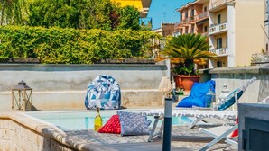 A poolside area with lounge chairs, a large blue bag, and a potted plant. - Villa Totti in Sant Agnello (Sant'Agnello)