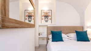 A hotel room with a bed, two pillows, a nightstand, a mirror, and two framed artworks on the wall. - Villa Totti in Sant Agnello (Sant'Agnello)