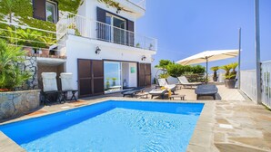 A swimming pool with lounge chairs and umbrellas, a stone-tiled deck, and a two-story building with balconies. - Casa Augusta A in Sorrento (Sorrento)