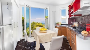 A modern kitchen with a view of the sea, a dining area with a table and chairs, and a red and white color scheme. - Casa Augusta A in Sorrento (Sorrento)