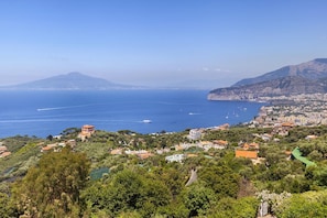 A coastal town with a view of the sea, buildings, and a mountain in the background.