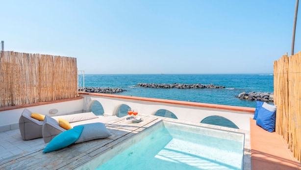 A rooftop pool with a view of the sea, lounge chairs, and a wooden fence. - Villa del Sole in Massa Lubrense (Massa Lubrense)
