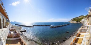 A coastal view with a rocky breakwater, clear blue sea, and buildings along the shore. - Villa del Sole in Massa Lubrense (Massa Lubrense)