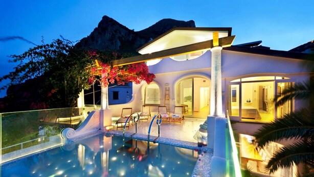 Une villa moderne dotée d’une piscine, d’un espace salon extérieur et offrant une vue sur les montagnes.