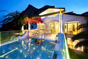 Eine moderne Villa mit Swimmingpool, Sitzgelegenheiten im Freien und Blick auf die Berge.