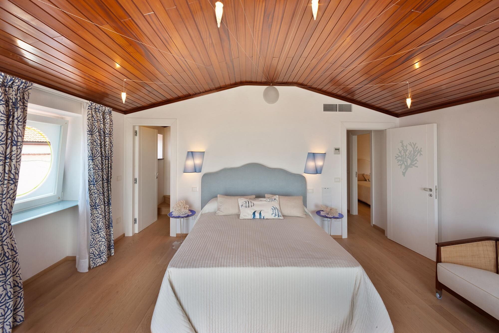 A bedroom with a large bed, wooden ceiling, and two bedside lamps.