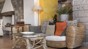 A living room with a glass coffee table, wicker sofa, and a lamp. - Residence Bosco - Villa Il Pino (Massa Lubrense)