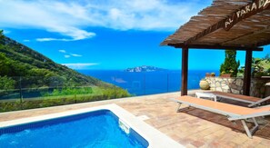 Zona de piscina con vista al mar y una montaña.
