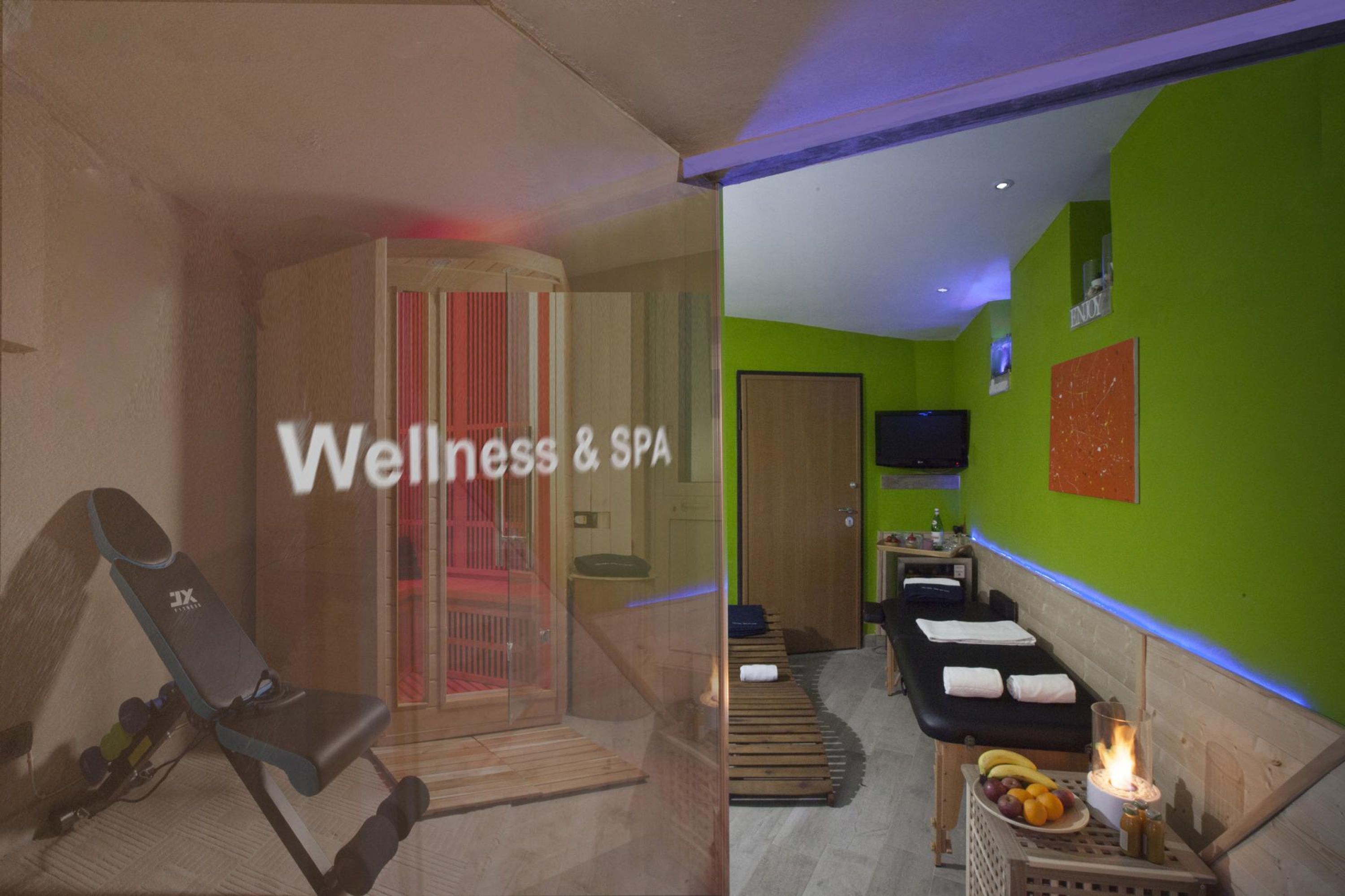 Een wellnessruimte met een massagetafel, een sauna en een ontspanningsruimte, compleet met fruitmand en kaarsen.