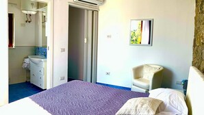A hotel room with a bed, a chair, a bathroom with a sink, and an air conditioning unit. - Casa Tatano in Massa Lubrense (Massa Lubrense)