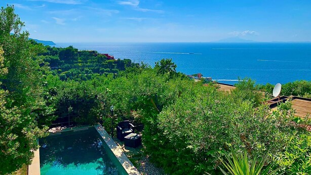 A pool surrounded by lush greenery, overlooking a coastal view with the sea and distant mountains. - Casa Tatano in Massa Lubrense (Massa Lubrense)