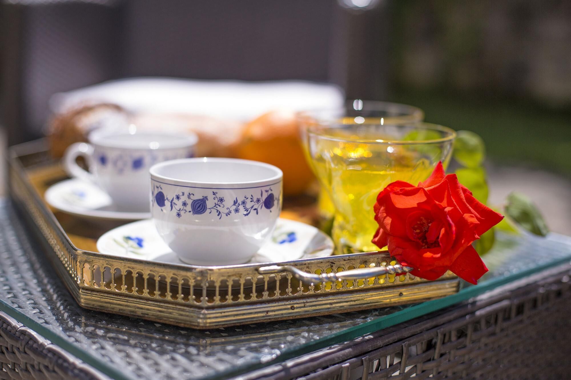 A tray with a teapot, cups, and a glass of tea with a rose.