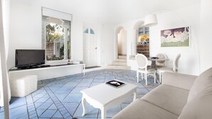 Un salon moderne doté d’un téléviseur à écran plat, de canapés blancs, d’une table basse et d’un coin repas avec des chaises.