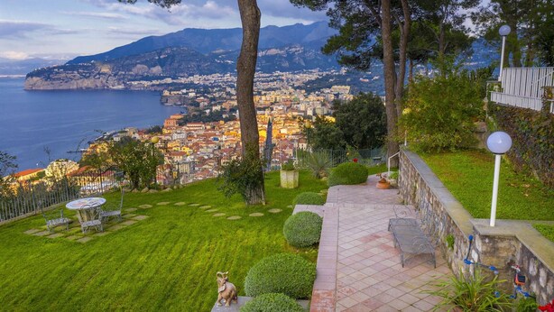 Une vue pittoresque d’une ville côtière, avec une zone herbeuse, une statue et une promenade dallée.