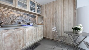 Une cuisine compacte avec des meubles en bois, un pare-feu en pierre et un petit coin repas comprenant une chaise et une table en métal.