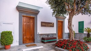 Villa, jossa on puinen ovi, kyltti, jossa lukee ”Villa Galidia – ylellinen lomakeskus”, ja pieni penkki ulkona.