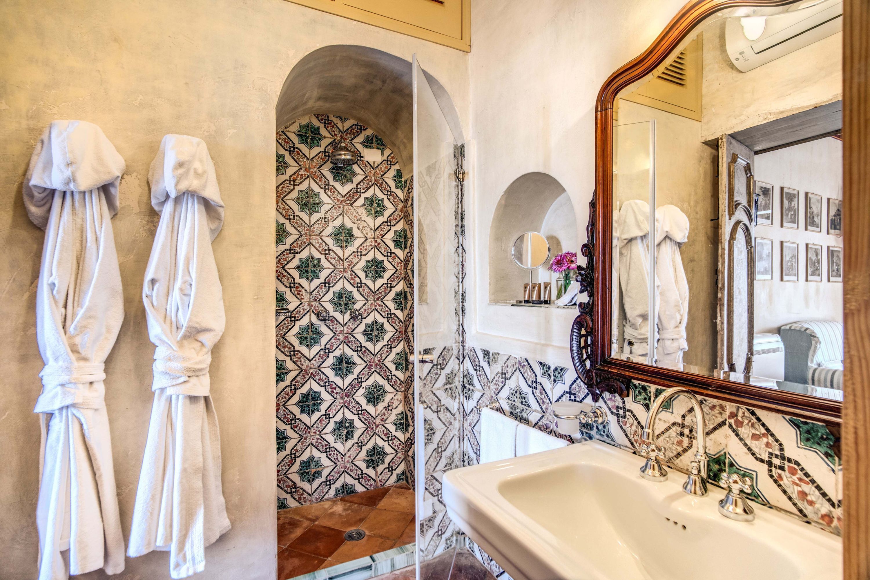 Une salle de bain avec un grand miroir, un lavabo et deux serviettes accrochées au mur.