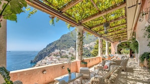 A terrace with wicker furniture, a glass table, and potted plants. - Villa San Giacomo in Positano (Positano)