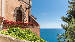 A building with a stone facade, a wooden door, and red flowers in front. - Villa San Giacomo in Positano (Positano)