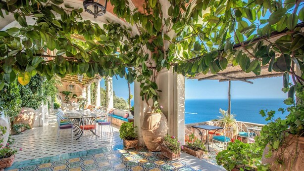 A terrace with a tiled floor, outdoor seating, potted plants, and a view of the sea. - Villa San Giacomo 1 in Positano (Positano)