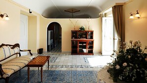 Un salon comprenant un canapé, une table basse, une bibliothèque et un vase décoratif avec des fleurs.