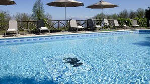 Une piscine d’un bleu éclatant, avec des chaises longues et des parasols.
