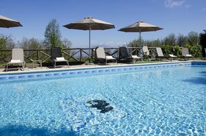 Une piscine d’un bleu éclatant, avec des chaises longues et des parasols.