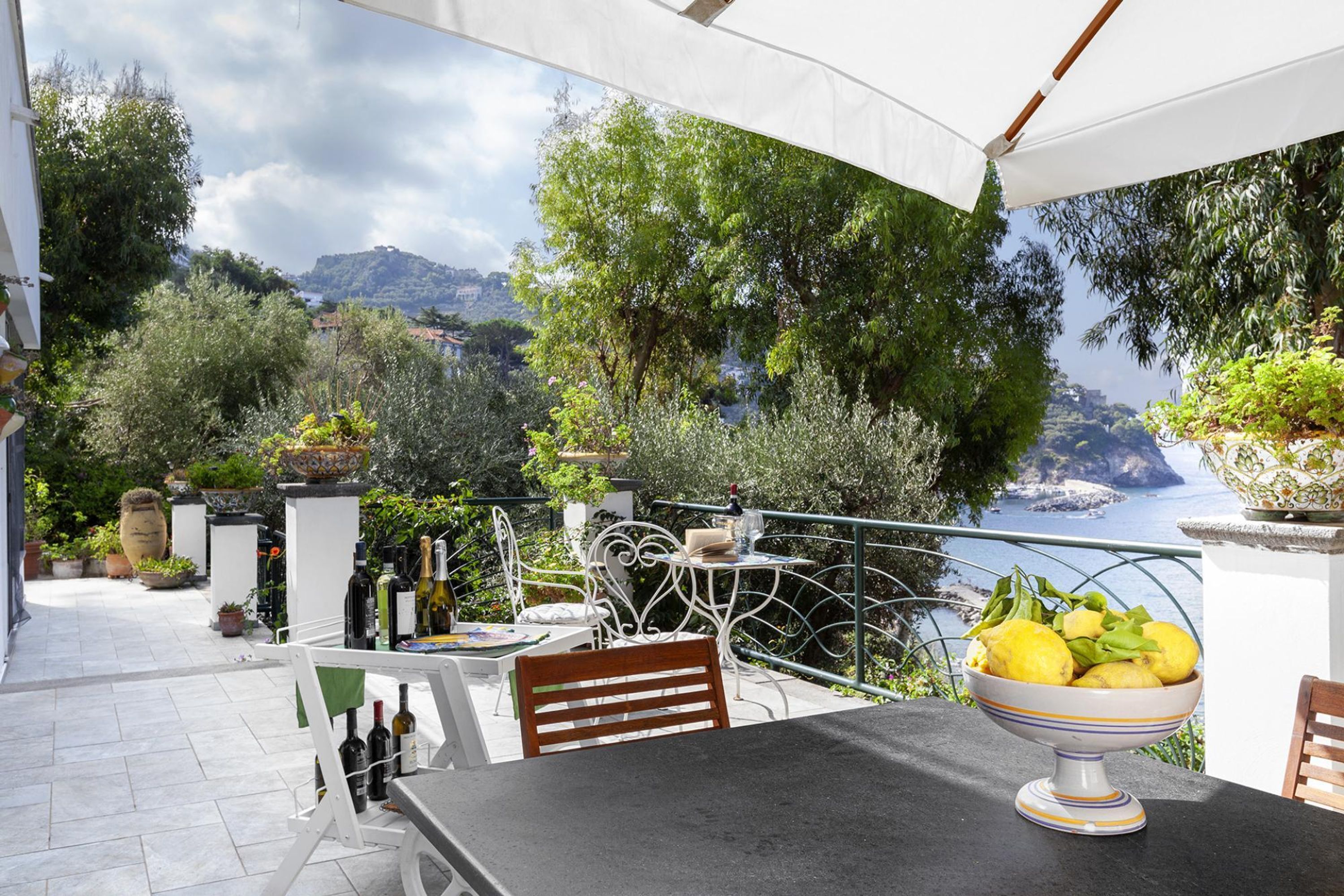 A terrace with a table, chairs, and a bowl of fruit.