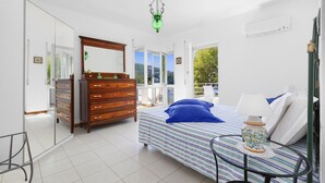 Un dormitorio con cama, cómoda y una mesita de noche con lámpara.