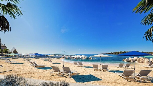 Una spiaggia con lettini, ombrelloni e un cielo azzurro intenso.