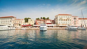 Un porto turistico con diversi yacht ormeggiati, circondato da edifici storici con tetti rossi e facciate bianche.