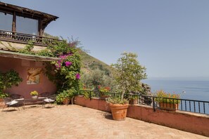 A coastal terrace with a wooden pergola, outdoor seating, and potted plants. - Villa Era in Positano (Vico Equense)